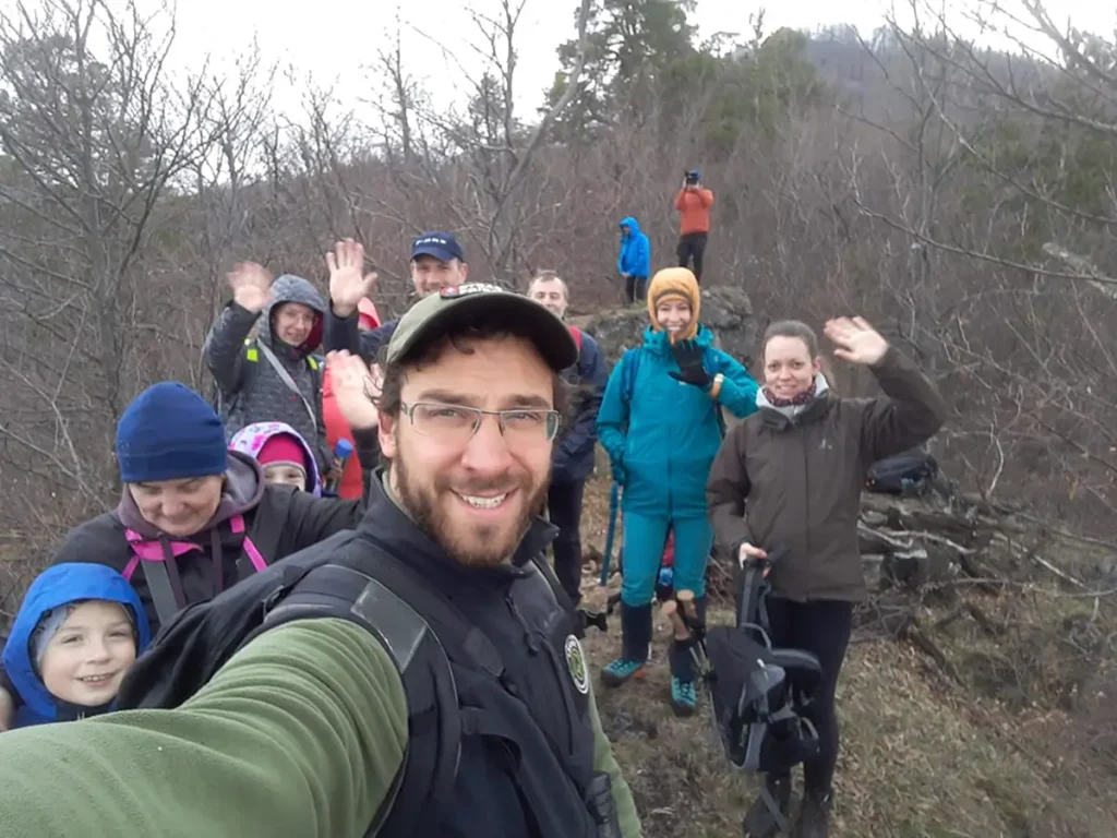 Guide taking a selfie with a smiling hiking group in spring forest